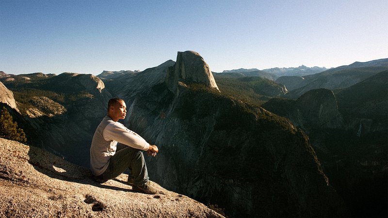 Man sitting with view of Half Dome, at Yosemite National Park