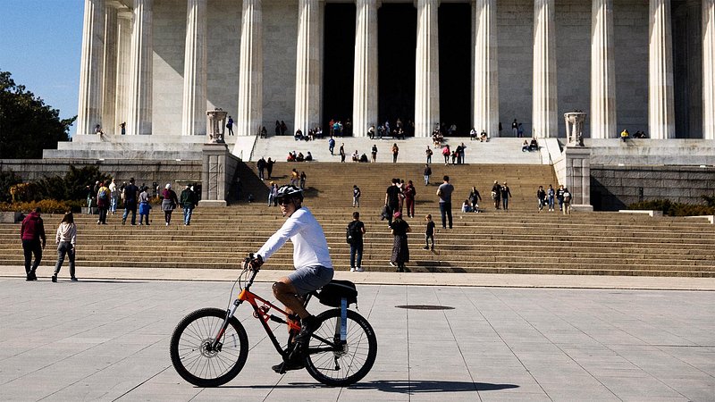 Man biking past the Lincoln Memorial, in Washington, D.C.
