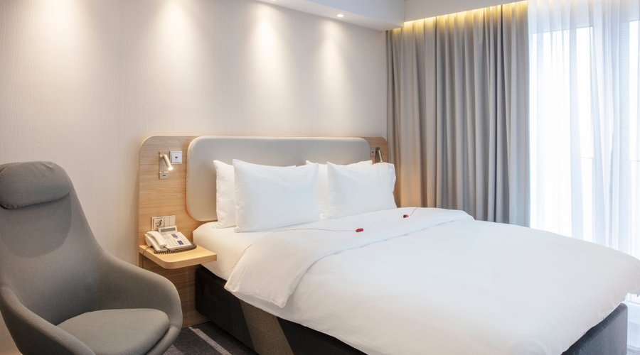 Airy accessible guest room with comfortable bed and swivel chair.