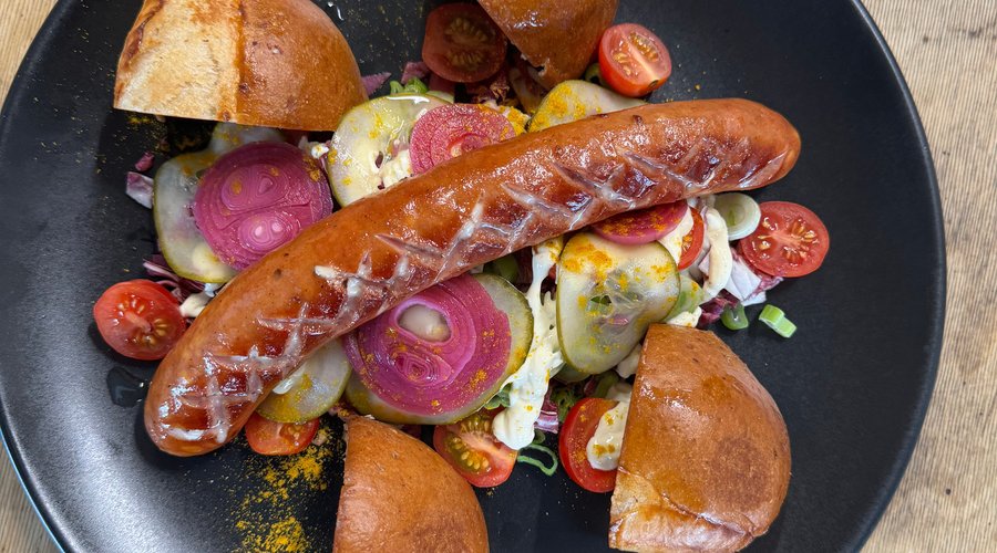 Sausage with cheese served with fresh vegetables and homemade bun
