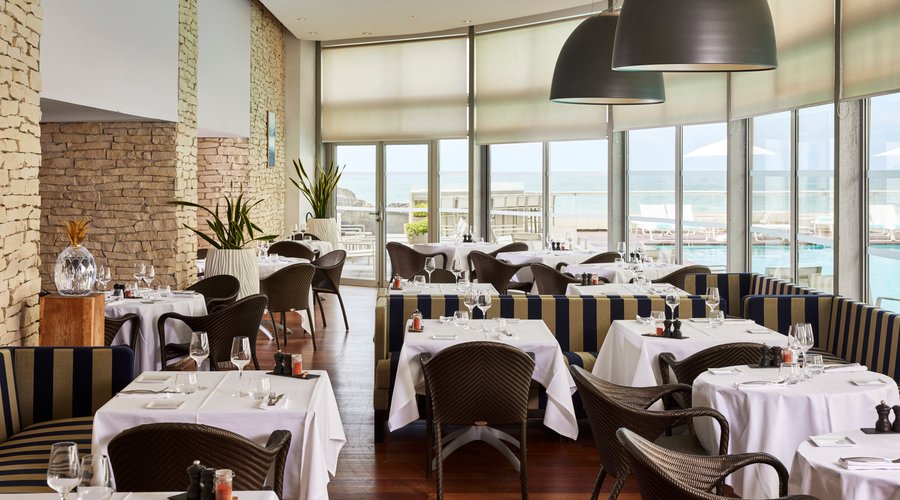 Salle de restaurant face à l'océan et au bord de la piscine panoramique.