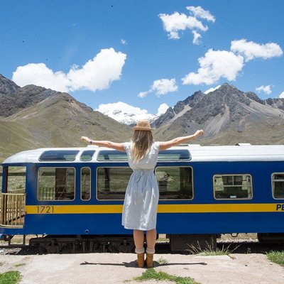 A woman posing in front of the The Lake Titicaca Train.