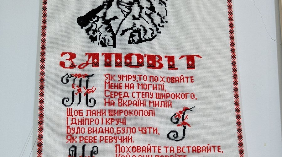 Um bordado com o rosto do poeta ucraniano Taras Shevchenko e algumas coisas escritas em Ucraniano.