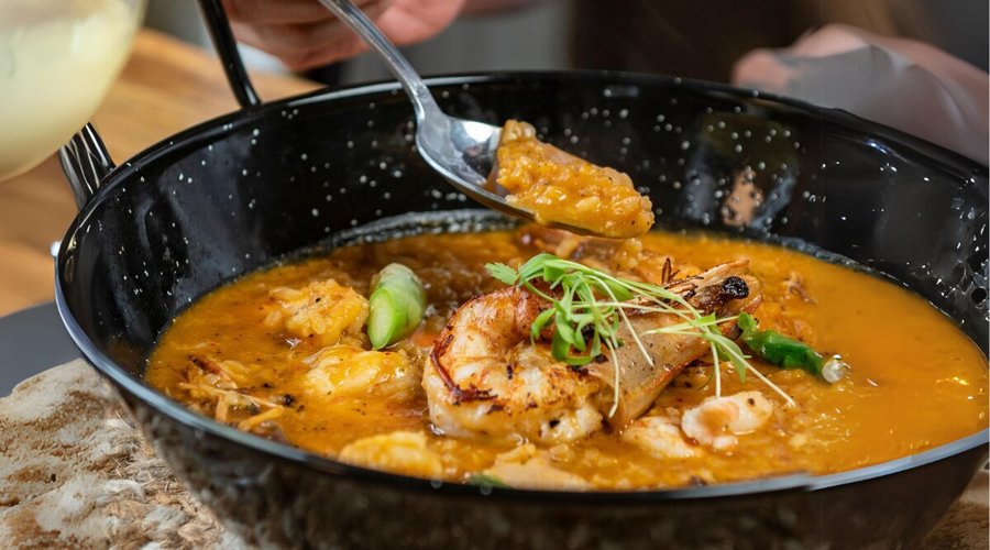 Arroz caldoso de langostinos y calamar, cocido con caldo de langostinos y tomate fresco, coronado con langostinos grillados y espárragos salteados en mantequilla.