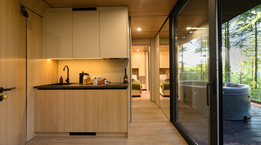 The kitchenette area with electric hob, kettle and sink. There is also a fridge concealed in the bottom cupboards. 