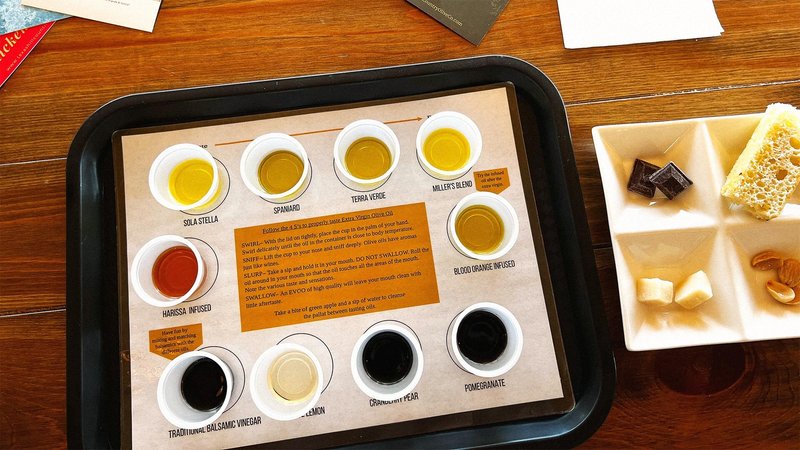 Tray of several cups of olive oil for tasting with accompanying foods like cheese and chocolate