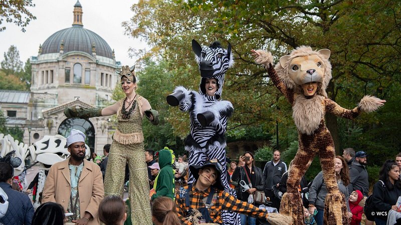 People on stilts and in animal costumes amid zoo-goers at Halloween event