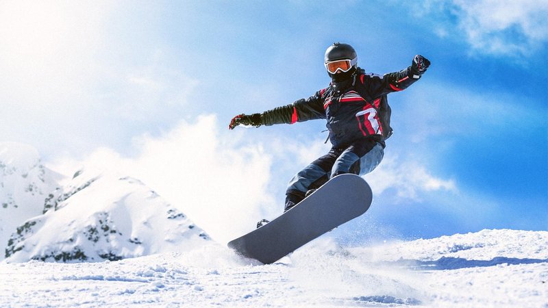 Person on snowboard in air over snowy mountain