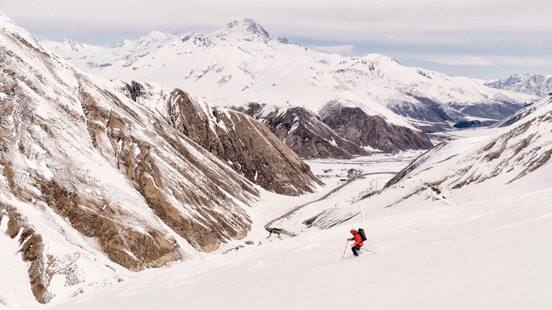 Person in red jacket skiing down snowy mountain