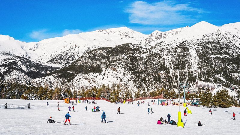 Lots of people skiing on snow with mountain behind them