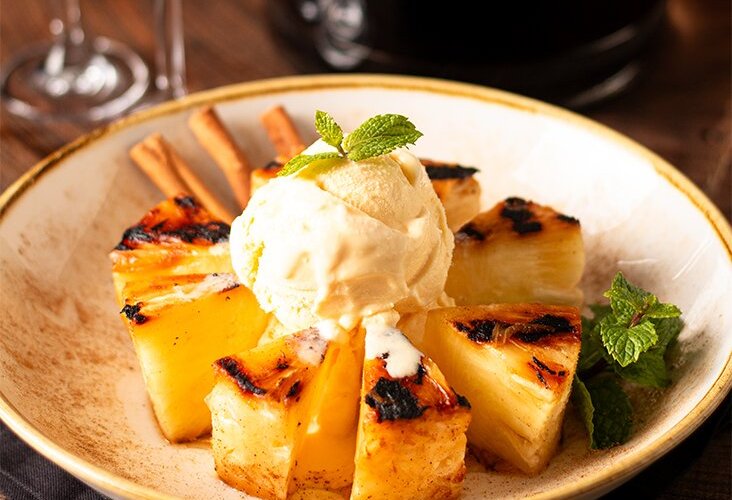 As sobremesas do Templo da Carne Marcos Bassi são o toque final perfeito para a sua experiência gastronômica. O destaque é o abacaxi grelhado na churrasqueira, caramelizado com açúcar e canela, servido com sorvete de creme, criando uma combinação irresistível de sabores. Para complementar, oferecemos vinhos de sobremesa e licores especiais, que fazem a transição perfeita entre o prato principal e o encerramento da refeição. Uma experiência completa para os amantes de sabores refinados.
