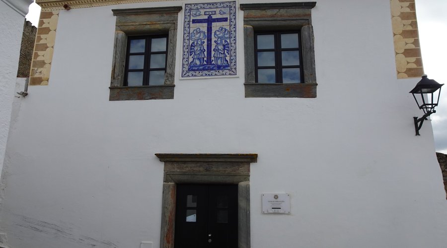 Wejście do budynku i tabliczka przy drzwiach o godzinach pracy .