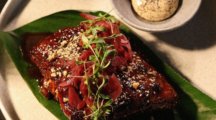 Costillas tipo St. Louis Preparadas en cocción lenta, terminadas con teriyaki de feijoa, encurtido de col y maní triturado. Servidas con baos y alioli de plátano frito, aguacate y cilantro.