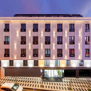 Dem Premium Hotel – Elegant and Modern Exterior  Dem Premium Hotel welcomes guests with a modern and stylish design. Conveniently located near Istanbul Airport, it features a sophisticated exterior, spacious entrance, and inviting ambiance. The bright lobby and contemporary architecture create a comfortable and peaceful environment, offering a relaxing stay away from the city's hustle.