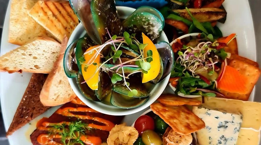 Rocks Rummage Board- Hot smoked salmon, Spanish chorizo, salt and pepper squid, battered onion rings, half shell mussels, marinated olives, blue cheese, brie, salad, crackers and crusty breads with house spreads.