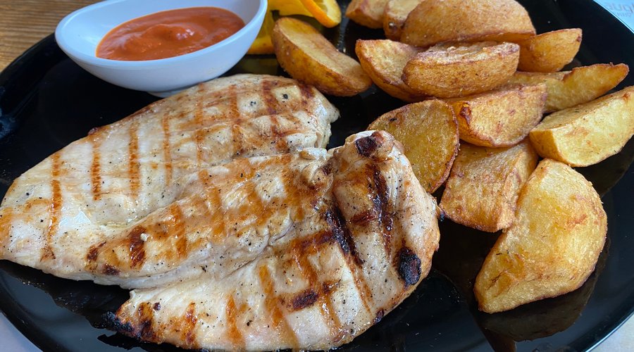 Chicken breast grilled on a volcanic stone grill with a side of baked potatoes and Spanish sause