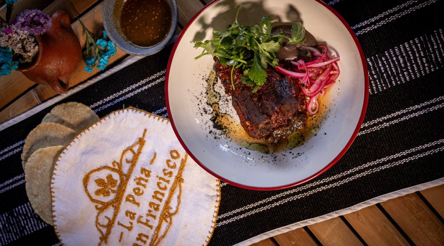 Costillas al Pibil.  Jugosa carne de cerdo de la región, cocida a la leña con nuestro achiote casero. Acompañada de frijoles refritos y tortillas recién hechas a mano. Un platillo lleno de sabor y tradición.