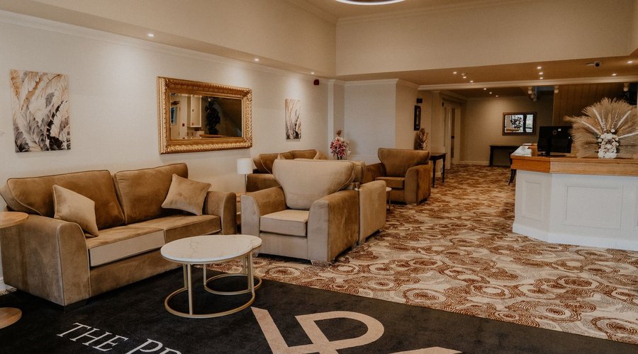 A welcoming hotel main reception area with comfortable sofas and soft, ambient lighting, creating a warm and inviting atmosphere for guests. The stylish design offers a relaxed space for visitors to check-in or unwind while enjoying the cozy, well-lit surroundings.
